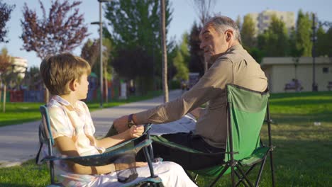 The-grandfather-is-chatting-with-his-grandson-outdoors.